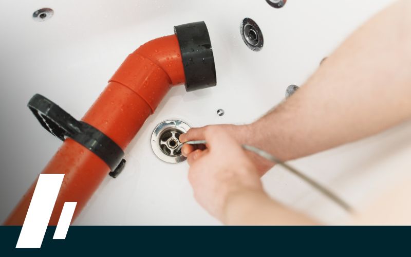 Close-up on the gloved hands of a drain specialist in Renton using a modern drain snake tool to efficiently clear a blockage.